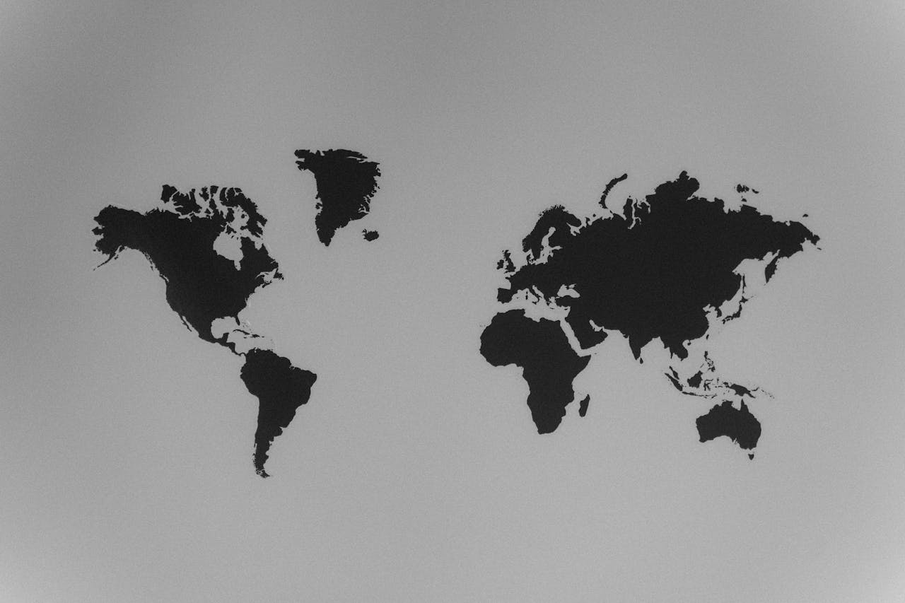 A simple black and white silhouette of a world map emphasizing continents against a stark background.